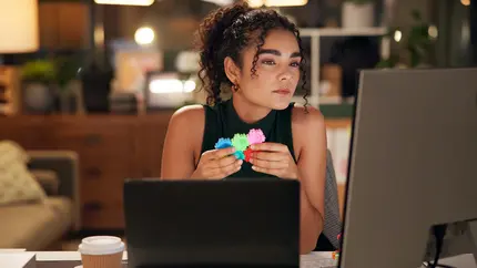 Female entrepreneur sitting at desk with fidget toy, working on a computer