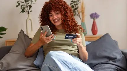 Woman on couch shopping on TikTok or other social media site as social commerce becomes new norm.
