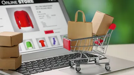compter screen showing retail site with clothing, in front, a miniature shopping cart depicting going shopping