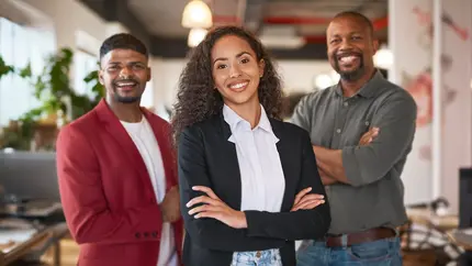 Three sibling entrepreneurs standing in an office two males on the left and right, female in the middle