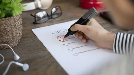Checklist on a business owner's desk with hand checking items off with pen.