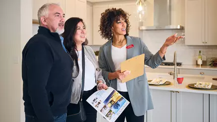 Female black real estate agent showing property to a man and woman