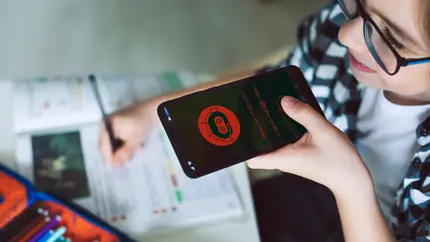Small business owner using an AI assistant on a smartphone while reviewing notes and planning work at a desk.