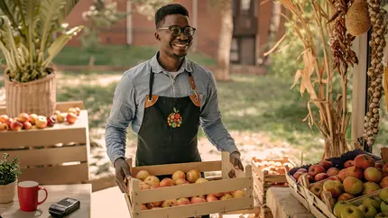 Small business owner at a local Georgia market arranging fresh produce for sale at an outdoor stand.