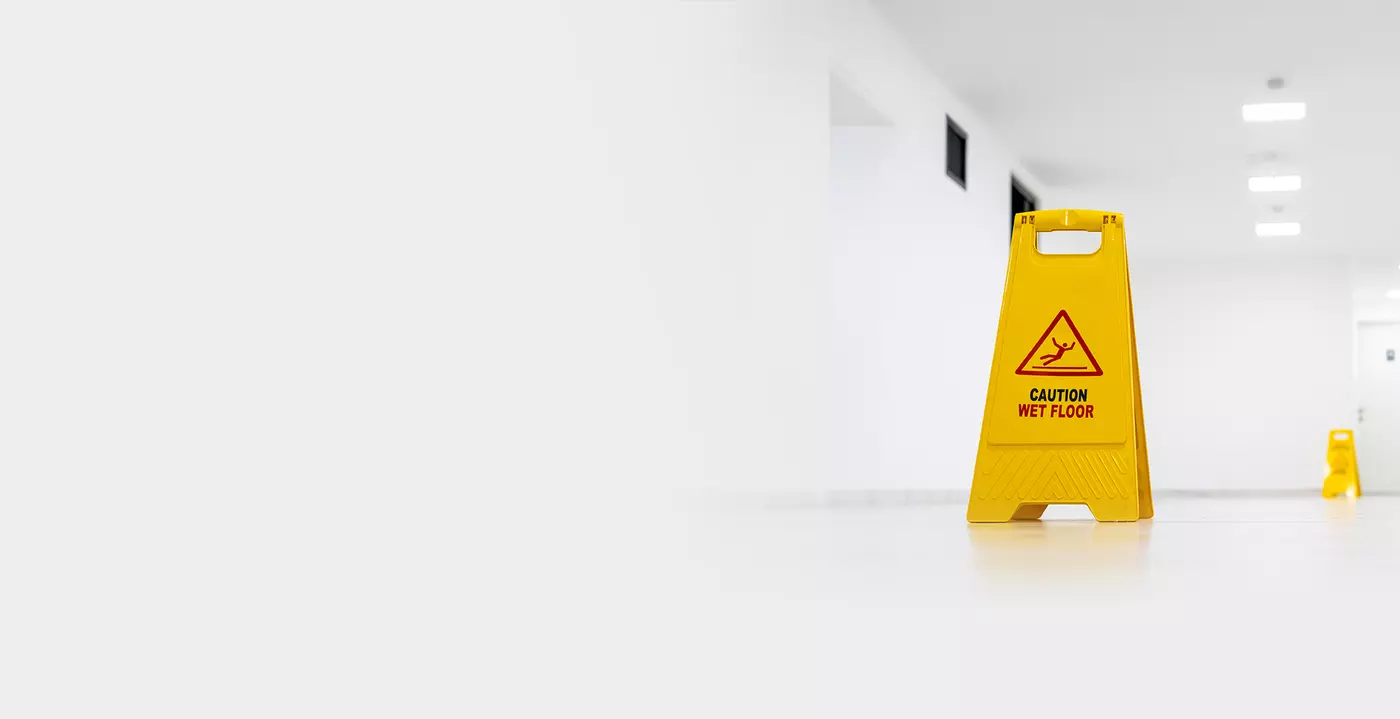 white empty room with a yellow sign that states "CAUTION WET FLOOR"