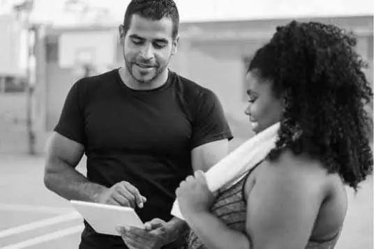 Personal trainer looking at paperwork with their fitness client