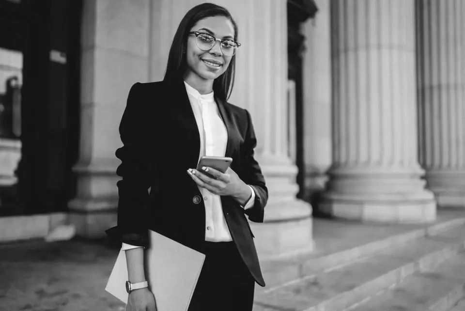 Woman holding a phone and file, standing in front of court building