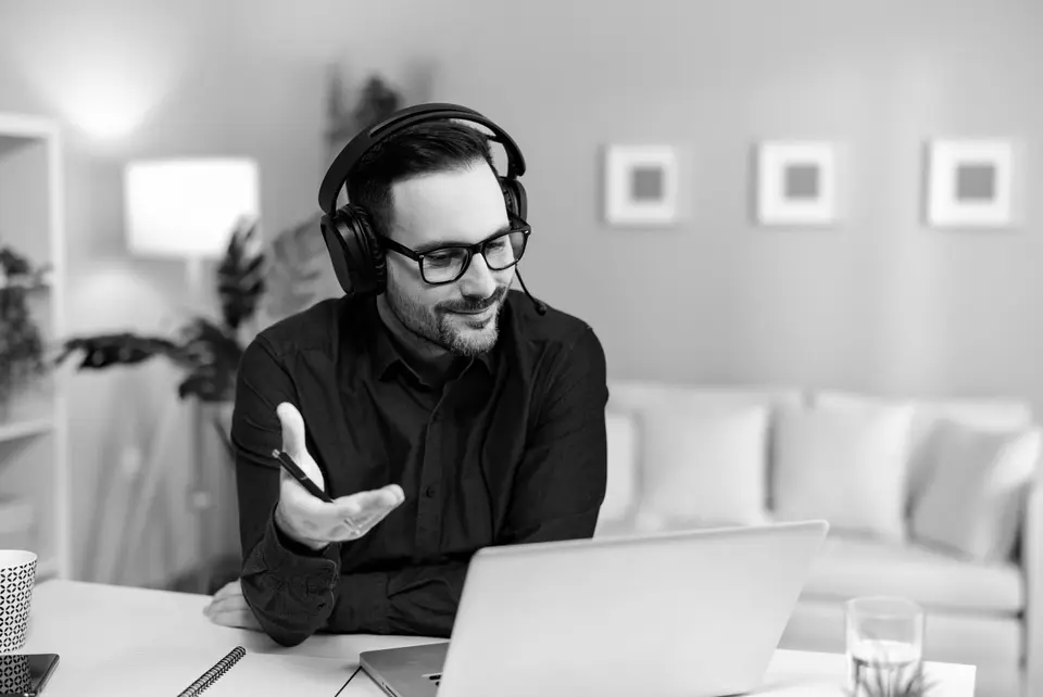 A mental health counselor wearing a headset sits in front of a computer for a virtual therapy session