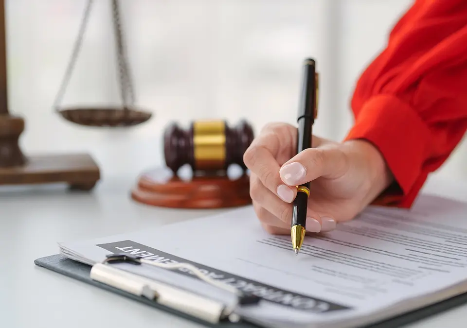 Hand signing a legal document with gavel in background