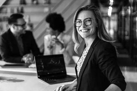 Marketer smiling at camera with two people talking in the background