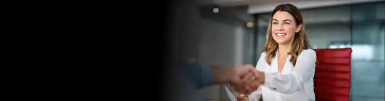 A white woman in a button-up shirt is shaking hands with a person offscreen